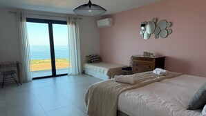 A bedroom with a bed, a chair, a dresser, and a view of the beach. - Villa Wonderfull sea view (Sari-Solenzara)