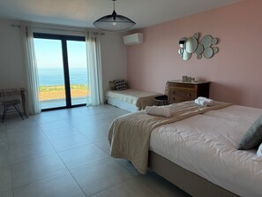 A bedroom with a bed, a chair, a dresser, and a view of the beach. - Villa Wonderfull sea view (Sari-Solenzara)