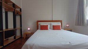 Ein Hotelzimmer mit einem großen Bett, einem Holz-Kopfteil, zwei Nachttischen mit Lampen, einem Schrank mit Spiegel und einem Fenster mit Vorhängen.
