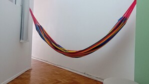 Ein Zimmer mit Hängematte, Holzboden, Deckenventilator und grüner Wand.
