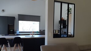 Een moderne keuken met een groot raam, een zithoek met stoelen en een bank.