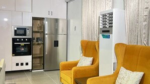 Et moderne køkken med indbyggede apparater, to gule lænestole og en stor aircondition.