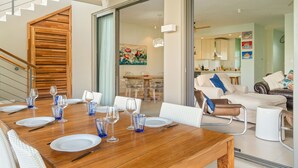 A dining area with a wooden table set for four, a staircase, and a living room with a sofa and coffee table. - Element penthouse with private pool near the beach (Cap Malheureux)