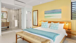 A bedroom with a large bed, a bench, a shower, and a painting of a beach. - Element penthouse with private pool near the beach (Cap Malheureux)