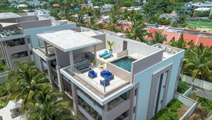 A multi-story building with a rooftop pool, outdoor seating, and surrounding greenery. - Element penthouse with private pool near the beach (Cap Malheureux)