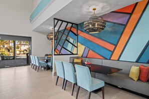 A modern dining area with a long table, blue chairs, and a colorful geometric wall design. - PG6043 - 15BR Amazing house near Disney (Orlando)