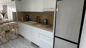 Eine moderne Küche mit weißen Schränken, einem Edelstahl-Kühlschrank und einem Holztisch mit Stühlen.