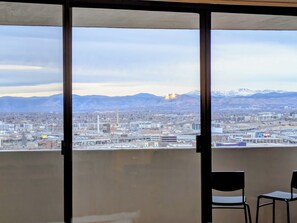 Ein Balkon mit Blick auf eine Stadtlandschaft, einschließlich Gebäude und Berge.