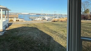 A view from inside a building looking out to a marina with boats, a bridge, and a grassy area.