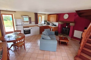 Un espacio habitable compacto con comedor, kitchenette, sofá y chimenea.