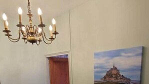 Een trap met een houten leuning, een kroonluchter en een schilderij van een kasteel aan de muur.