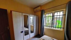 Ein Schlafzimmer mit Bett, Kleiderschrank und Fenster mit Gittern.