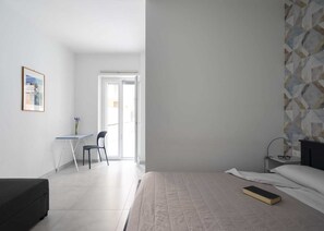 Ein Schlafzimmer mit Bett, Schreibtisch, Stuhl und Fenster.