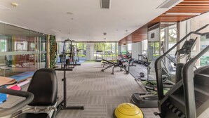 A gym with exercise equipment, a yellow exercise ball, and large windows. - Shanghai Bund Suhepan Apartment (Shanghai)