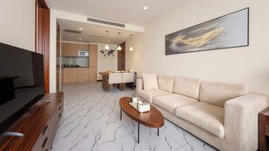 A modern living room with a sofa, coffee table, TV, and a dining area with a kitchen in the background. - Shanghai Bund Suhepan Apartment (Shanghai)