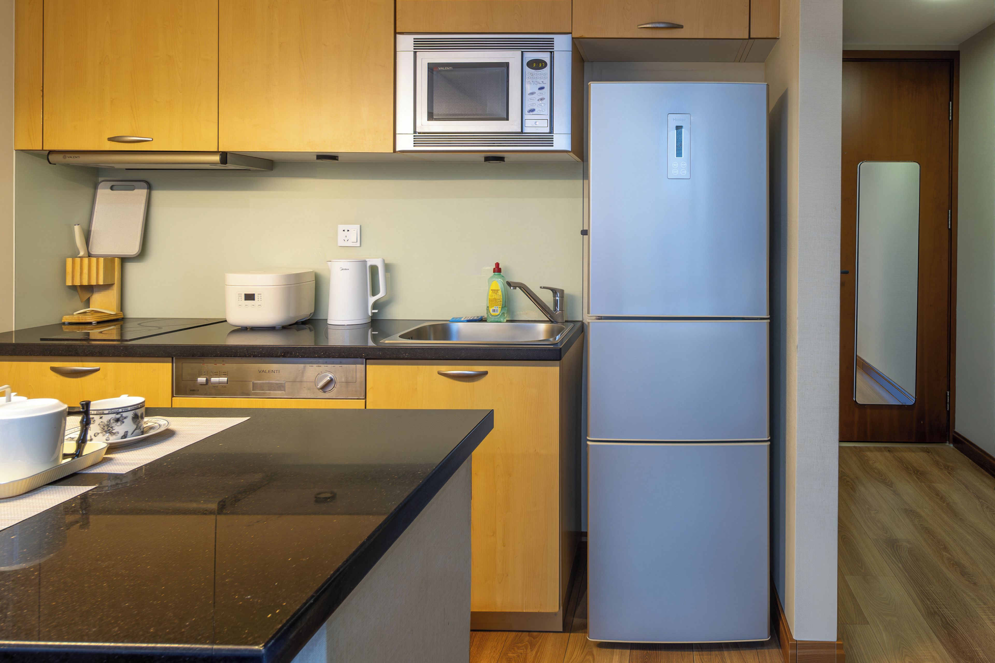 A compact kitchen with a microwave, a refrigerator, a coffee maker, and a dishwasher.