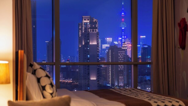 A hotel room with a large window offering a cityscape view at night. - Shanghai Bund Suhepan Apartment (Shanghai)