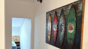 Un couloir orné d’une œuvre d’art murale en bois représentant des planches de surf et des destinations comme Hawaï et Maui.