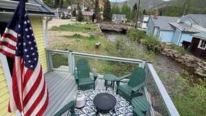 A deck with green chairs and a table, overlooking a river and a mountainous landscape. - Lovely 2 bed 1 bath home on  Creek in mountains w/deck, hot tub 2 King & 1 Queen (Silver Plume)