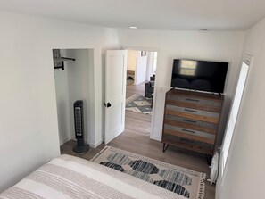 A bedroom with a bed, a dresser, a television, and a heater.