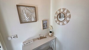 Een muur met een lijstwerk van een blad, een lijst met foto van ijsberen, een macramé wanddecoratie, en een 'HOME' bordje op een witte console tafel.