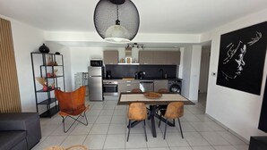 Een moderne keuken met een eethoek, inclusief een tafel met stoelen, een bank en een decoratieve plank.