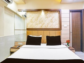 Une chambre d’hôtel avec un lit, une table de chevet, un climatiseur fixé au mur et une porte.
