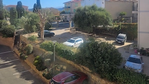 Ein Parkplatz mit mehreren Autos, eine Kirche mit zwei Türmen und ein Wohngebäude mit einem Balkon.