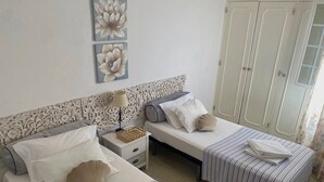 A bedroom with two beds, a nightstand, a decorative headboard, and a wardrobe. - Al Mare Ocean View (Albufeira)