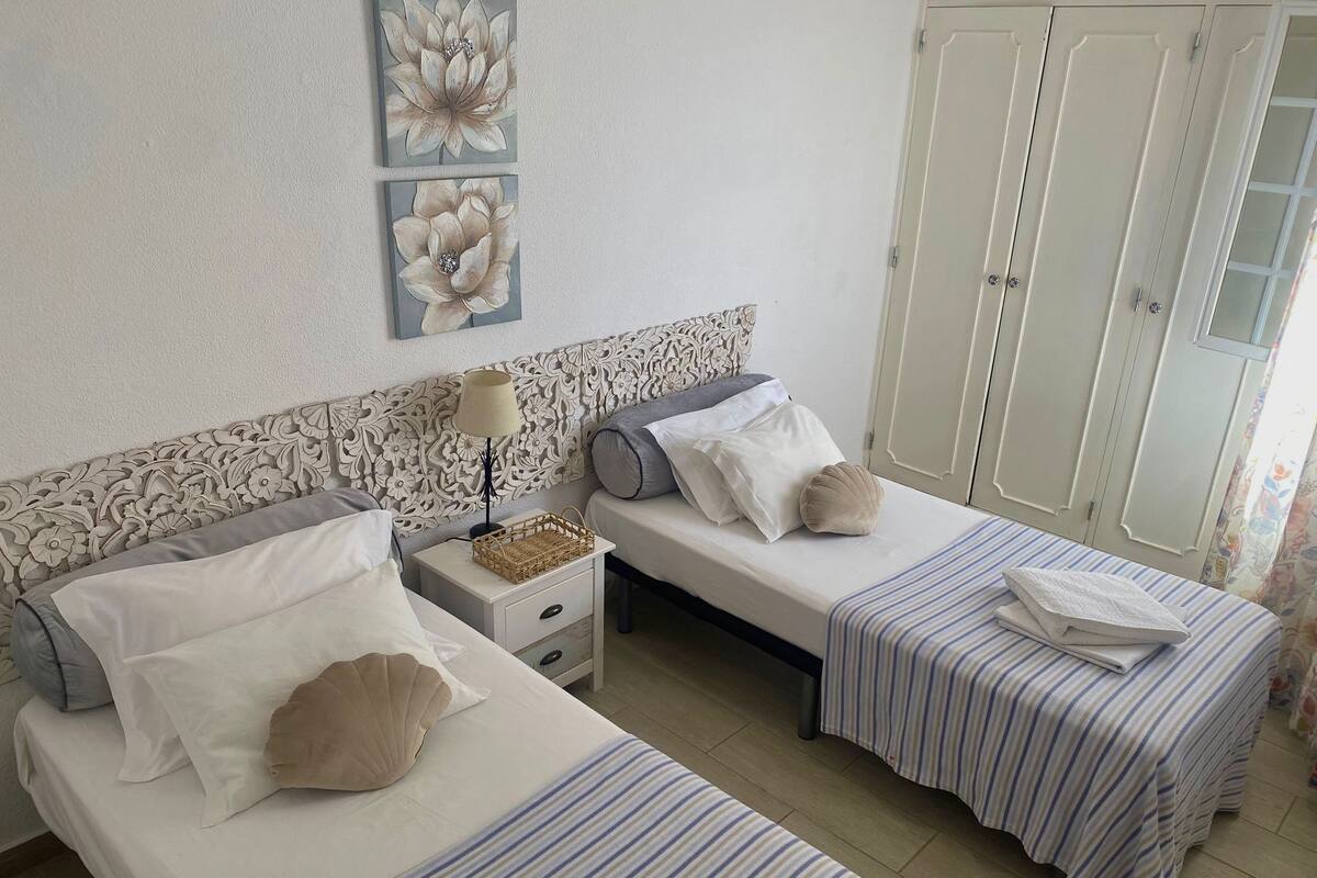 Une chambre avec deux lits, une table de chevet, une tête de lit décorative et une armoire.