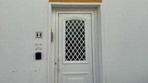 A white door with a lattice design, a number plate above it, and a small black intercom on the wall. - Al Mare Ocean View (Albufeira)