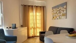 A dining area with a table and chairs, a kitchen area with a counter and appliances, and a window with curtains. - Al Mare Ocean View (Albufeira)