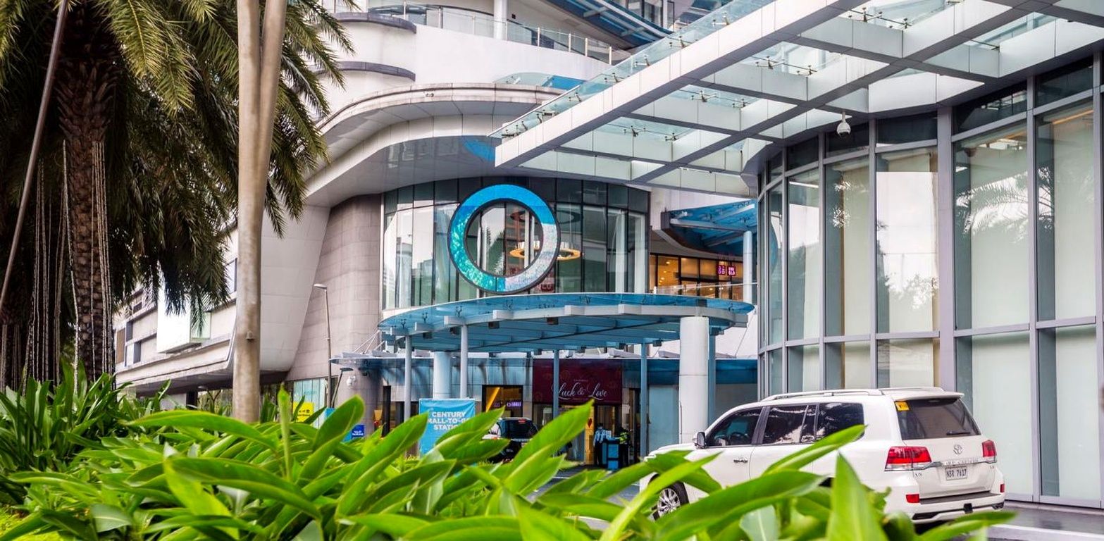 Un bâtiment moderne doté d’une entrée incurvée, d’une façade en verre et d’un élément décoratif circulaire de couleur bleue.