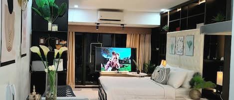 Una sala de estar moderna con un televisor de pantalla plana, un sofá, una mesa de comedor y plantas decorativas.
