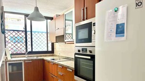 Una cocina con gabinetes de madera, horno empotrado, microondas y refrigerador.