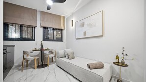 A modern bedroom with a bed, a dining table, chairs, a small side table, a vase with flowers, and a painting on the wall. - Prime Central Location Mahane Yehuda Market (Jerusalem)