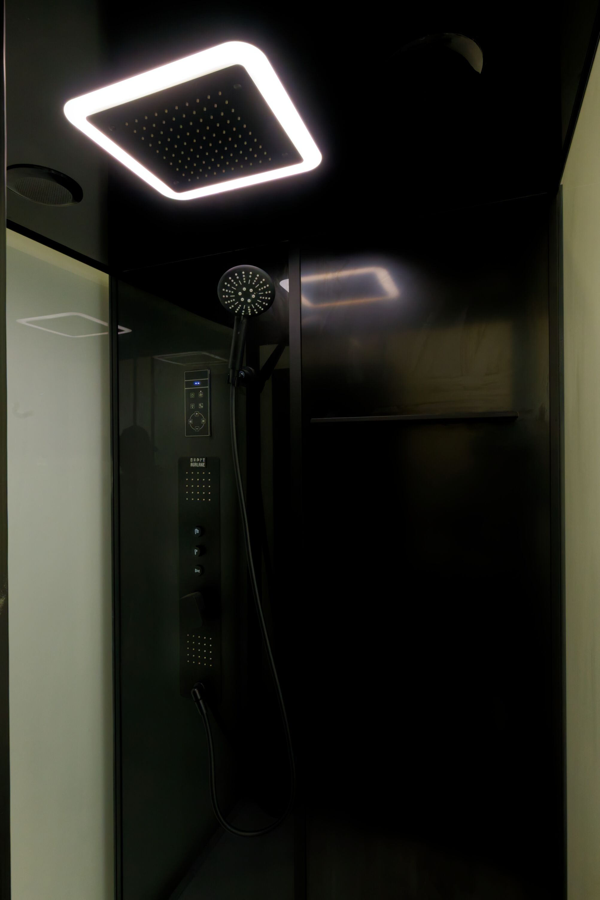 A modern shower with a square LED light fixture above the control panel.