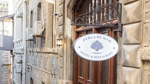A hotel sign with 'PERLA DE MAR HOTEL & RESTAURANT' and a door with a metal railing. - Governor Park Hotel (Baku)
