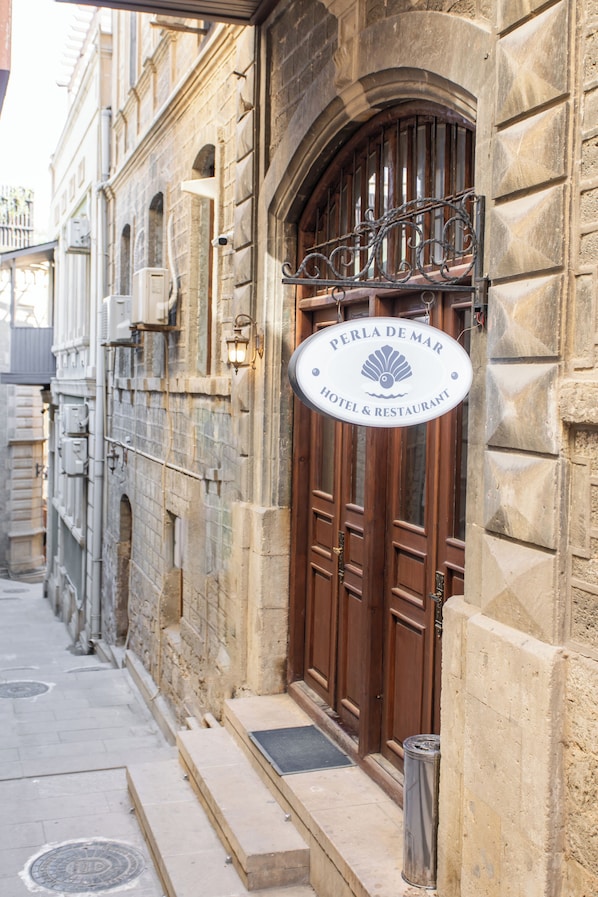 A hotel sign with 'PERLA DE MAR HOTEL & RESTAURANT' and a door with a metal railing.