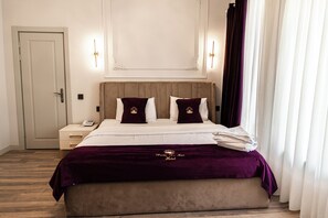 A hotel room with a large bed, a bedside table, a nightstand, and a door.