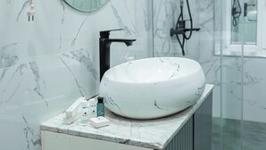 A bathroom with a marble sink, a hairdryer, a mirror, and a shower area. - Governor Park Hotel (Baku)