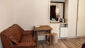 A compact room with a brown leather sofa, a small wooden table, a white refrigerator, and a small stool. - Governor Park Hotel (Baku)