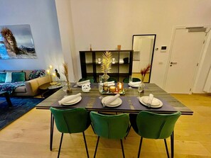 A dining area with a table set for four, green chairs, and a bookshelf in the background. - Antwerp Retreat With Kosher Kitchen (Antwerp)