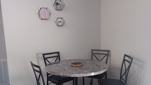 Un espace repas comprenant une table ronde, quatre chaises et trois éléments de décoration hexagonaux fixés au mur.