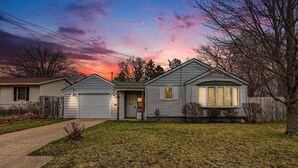 A two-story house with a garage, a front porch, and a well-maintained lawn. - Cozy Muskegon Getaway Near Lake Michigan with Pool (Muskegon)