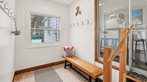 A room with a bench, a window with a view of a house, a wall-mounted fan, and a door leading to another room. - Cozy Muskegon Getaway Near Lake Michigan with Pool (Muskegon)