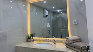 Une salle de bain avec un lavabo en marbre, une douche en verre et un grand miroir.