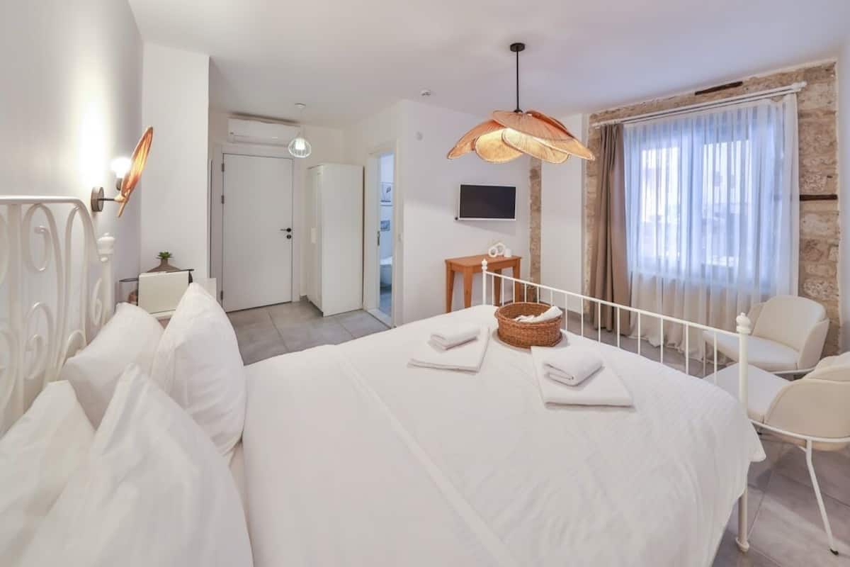 A hotel room with a bed, a chair, a television, and a window with curtains.