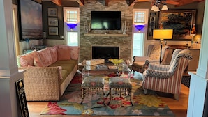 Una sala de estar acogedora con chimenea, televisión y alfombra estampada.