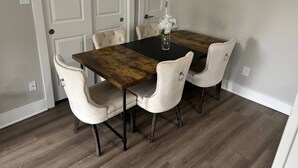 Una mesa de comedor con cuatro sillas, un florero con flores y piso de madera.